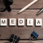 Workspace desk with word media spelled in wooden blocks. captioned online video