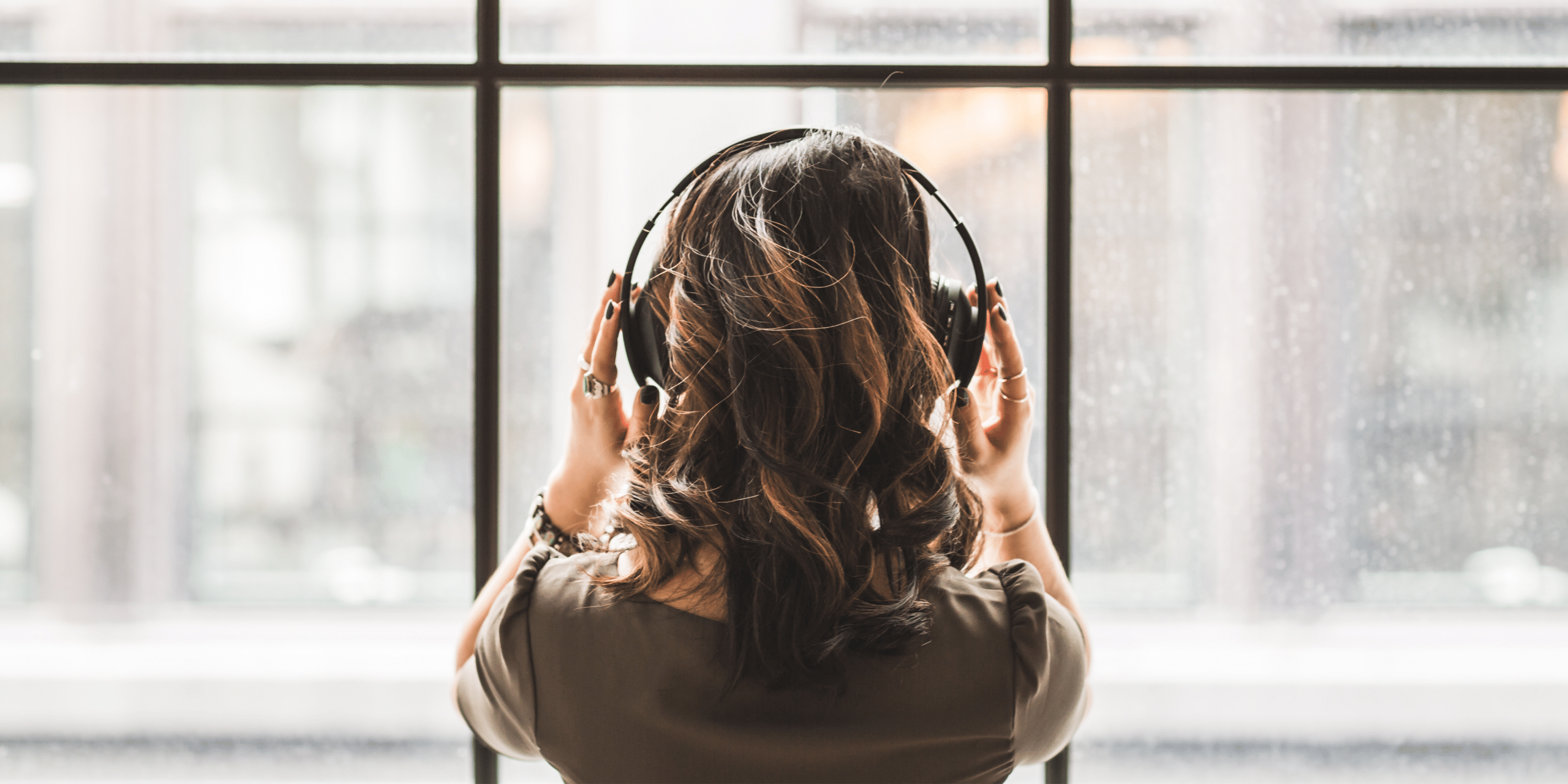 Person using headphones while looking out a window